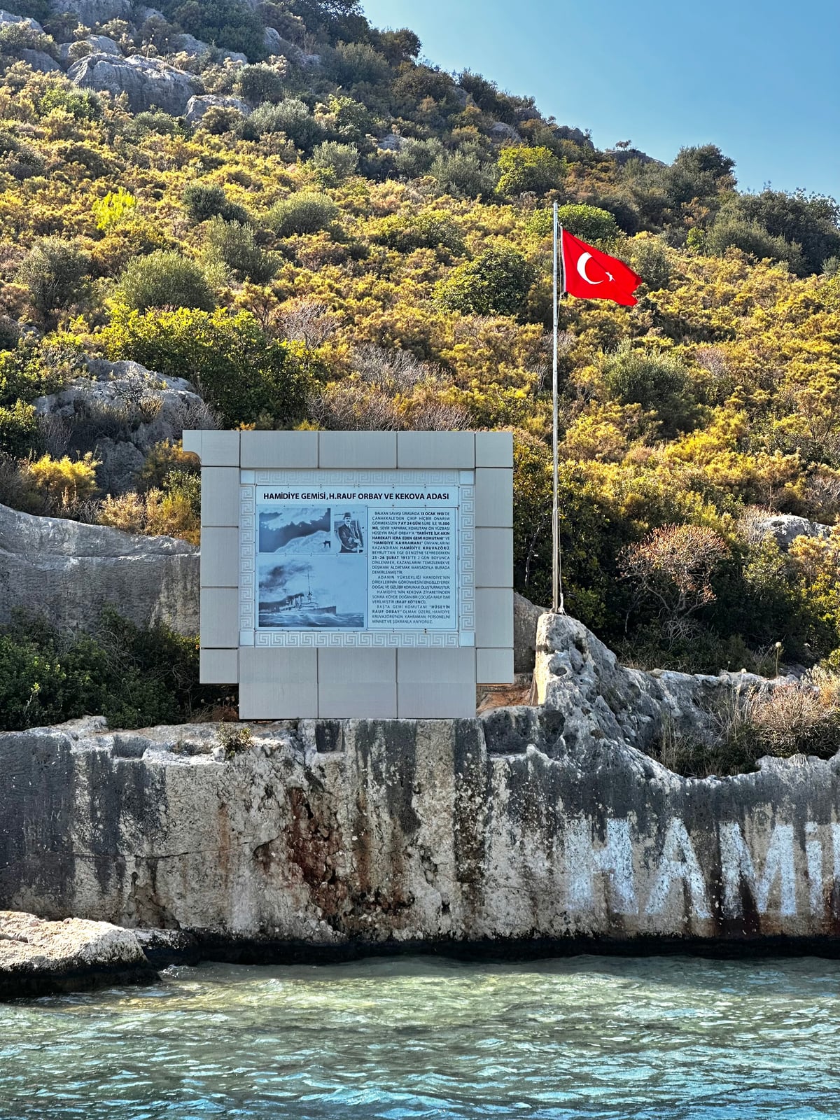 Hamidiye Koyu’ndaki anıt levhası ve kayaya boyanmış Türk bayrağı, Kekova