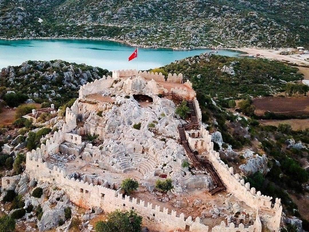 Simena Castle from the air — the small ancient theatre inside the walls, with the bay and mountains behind